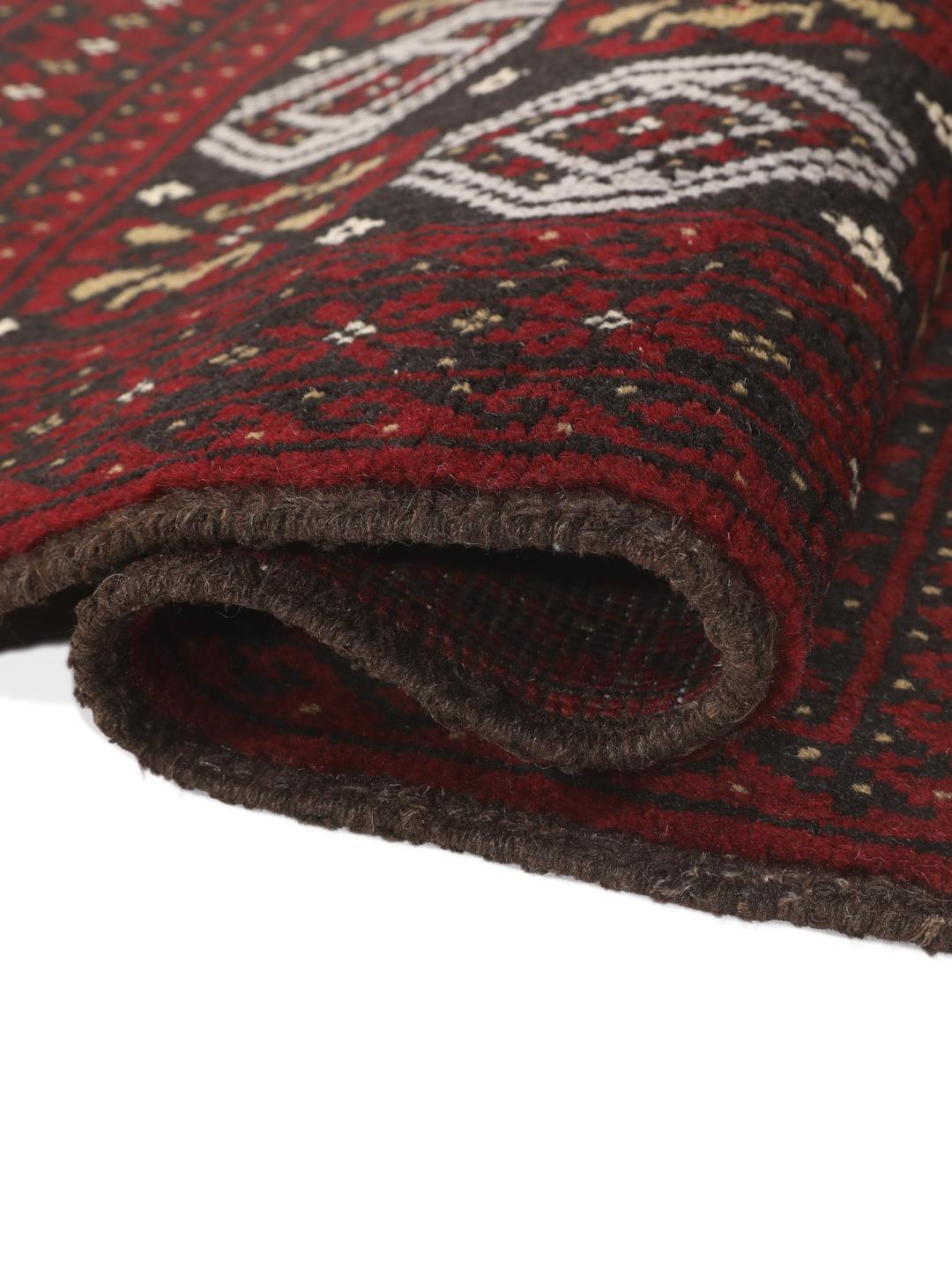 A small, one-of-a-kind Baluch rug from the Middle East with a dark-red and black geometric pattern.
