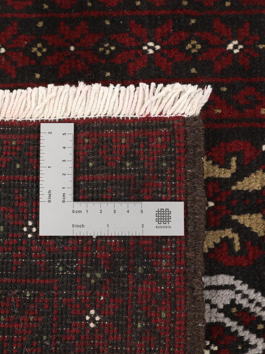 A small, one-of-a-kind Baluch rug from the Middle East with a dark-red and black geometric pattern.