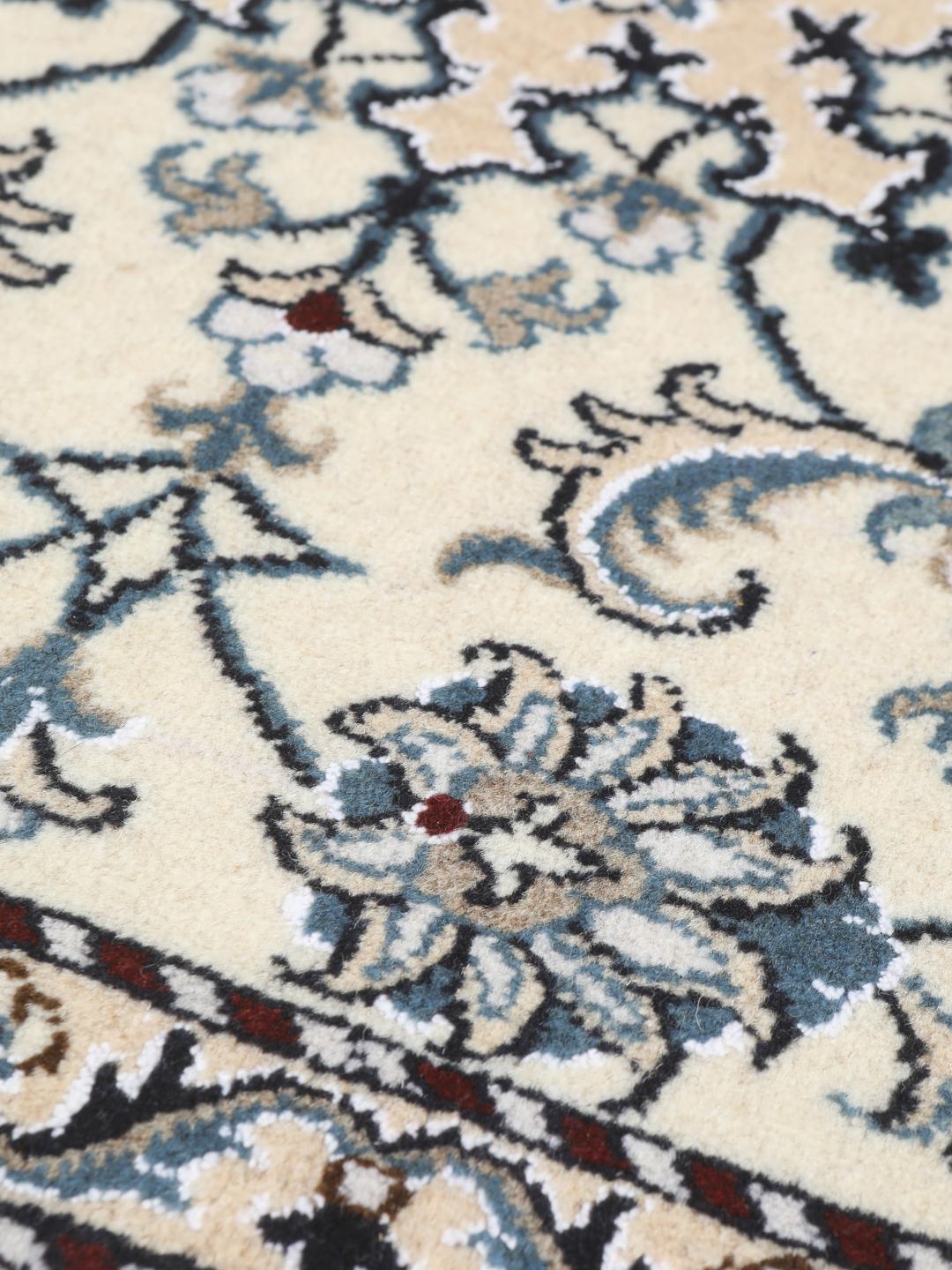 A hand-knotted floral Nain rug from the Middle East in beige and blue tones.
