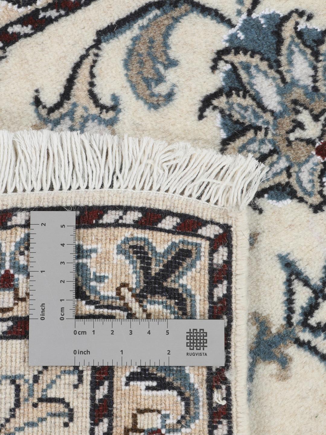 A hand-knotted floral Nain rug from the Middle East in beige and blue tones.