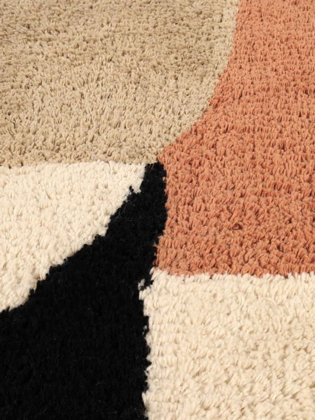 Un tapis de bain en coton doux avec un motif géométrique beige, terracotta et noir