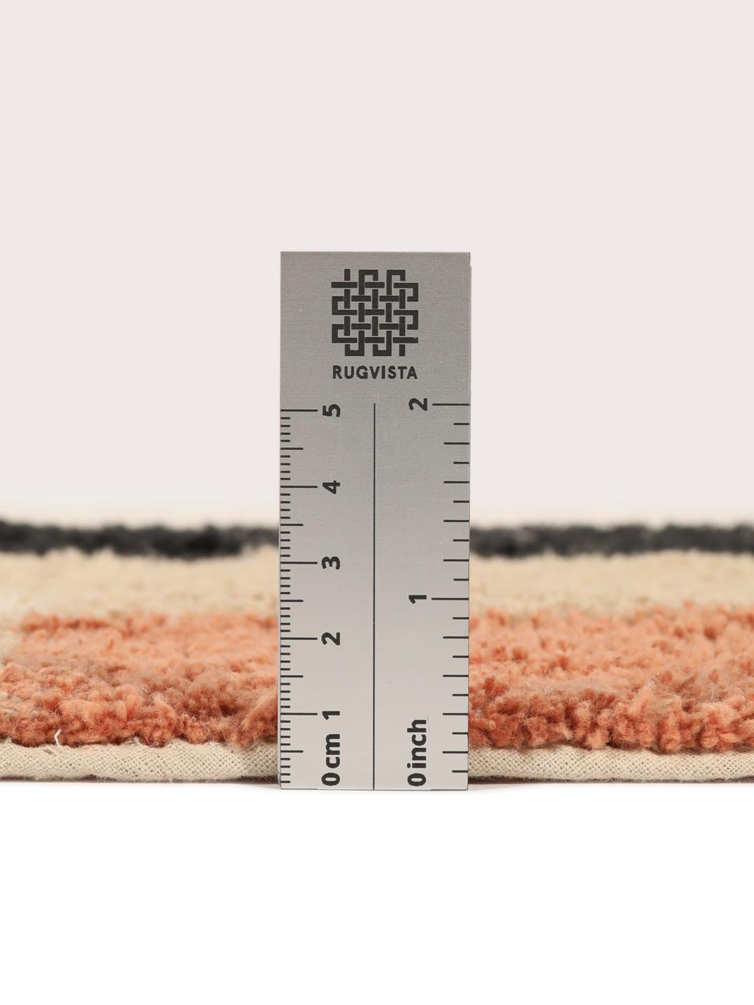 Un tapis de bain en coton doux avec un motif géométrique beige, terracotta et noir