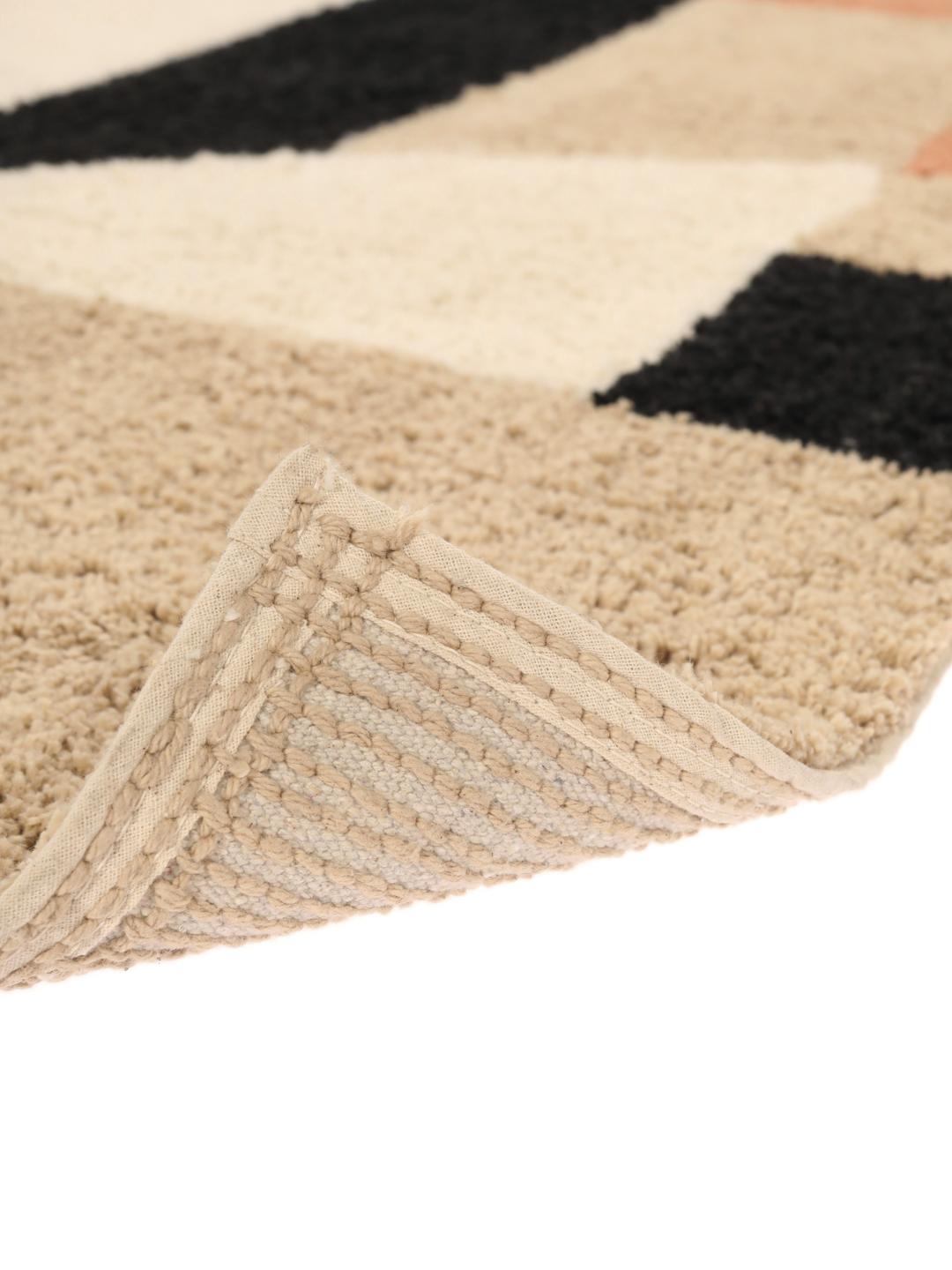 Un tapis de bain en coton doux avec un motif géométrique beige, terracotta et noir