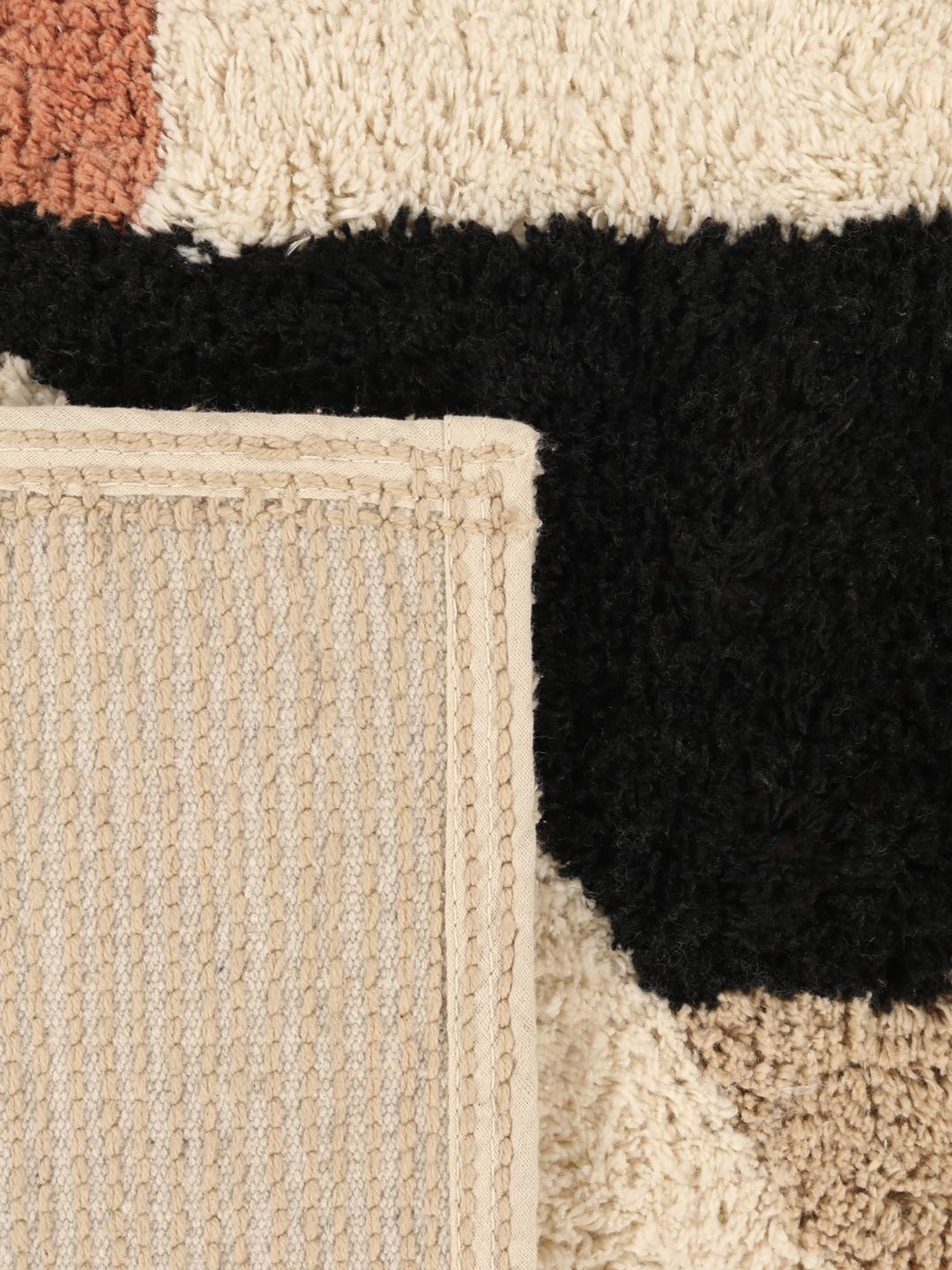 Un tapis de bain en coton doux avec un motif géométrique beige, terracotta et noir
