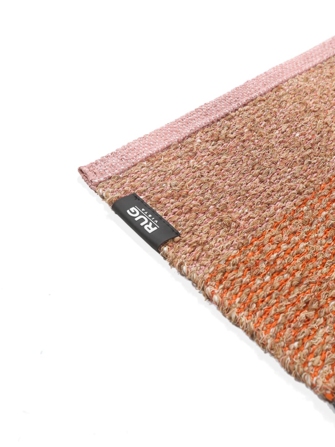 Een rechthoekig tapijt met koraalrode, oranje en beige gestreepte patronen met geometrische accenten.