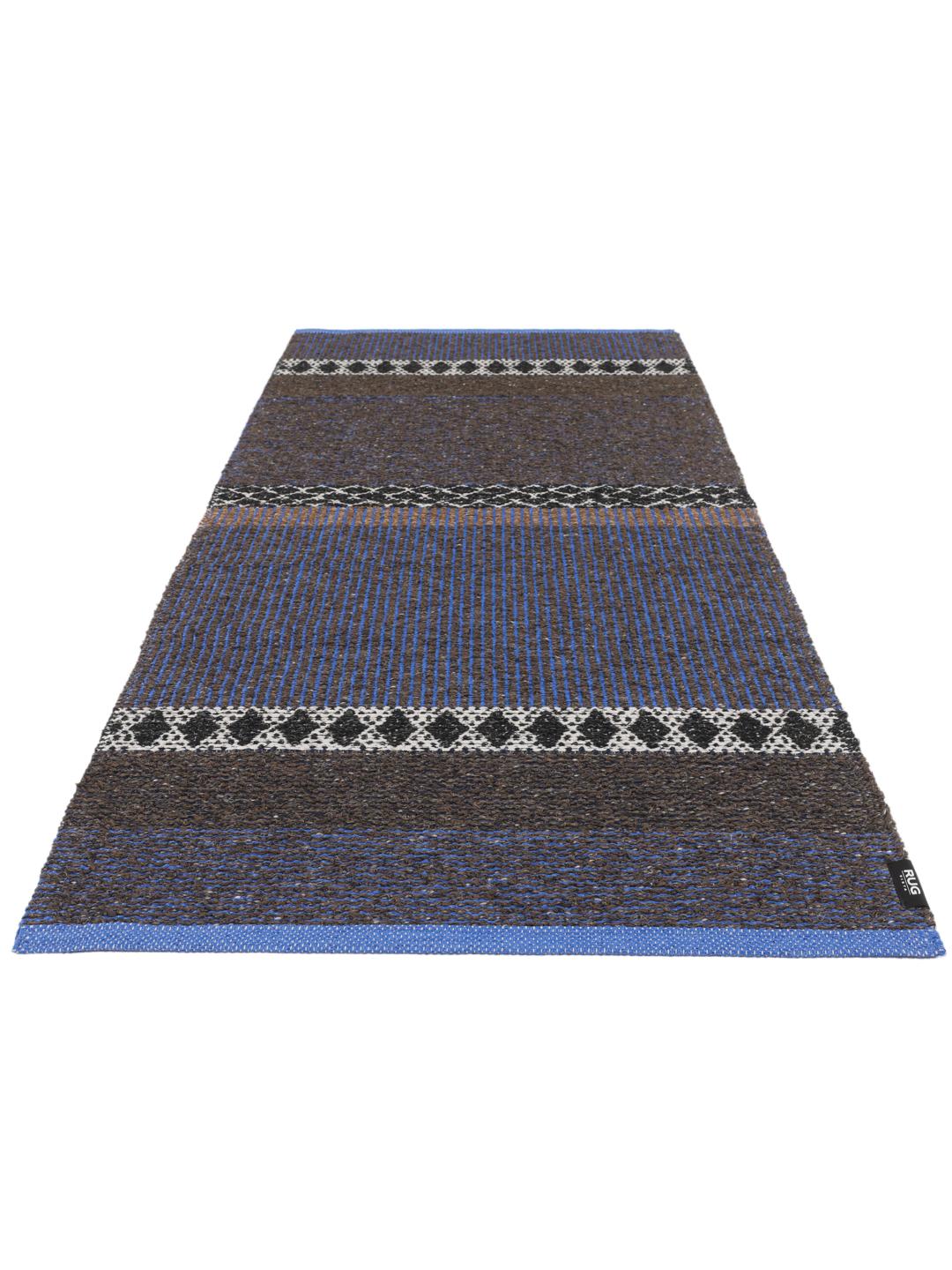 Een rechthoekig geweven tapijt in blauw en bruin met een herhalend geometrisch patroon.