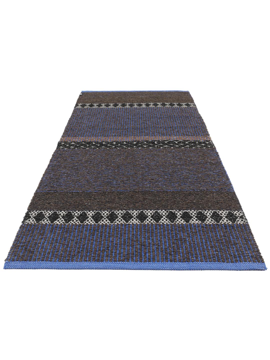 Een rechthoekig geweven tapijt in blauw en bruin met een herhalend geometrisch patroon.