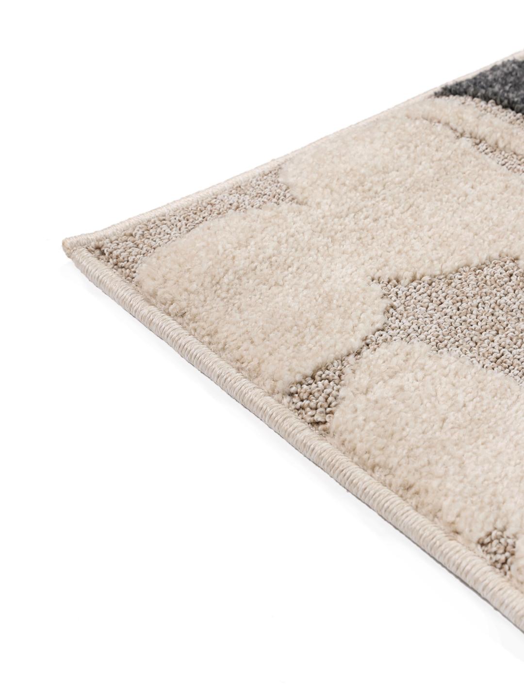Un tapis pour enfant beige et gris présentant un motif de mouton stylisé avec une texture à poils longs et courts.
