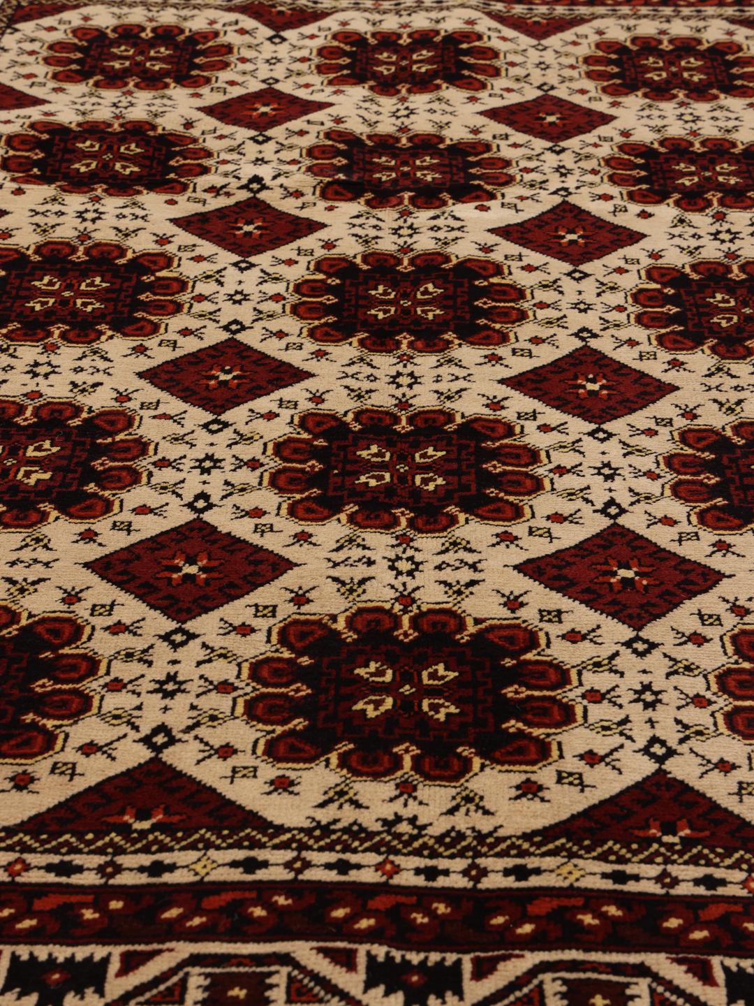 Et håndknyttet Kunduz-tæppe fra Afghanistan med geometriske motiver i rød og beige.