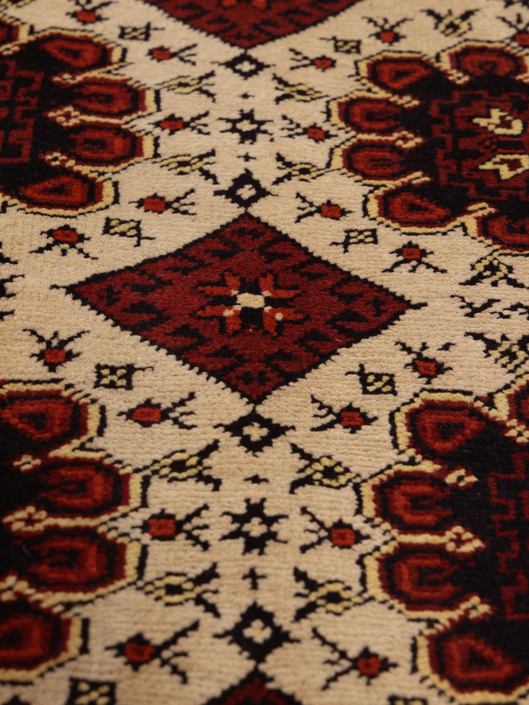 Et håndknyttet Kunduz-tæppe fra Afghanistan med geometriske motiver i rød og beige.