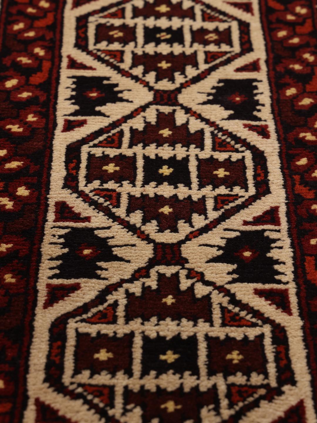 Et håndknyttet Kunduz-tæppe fra Afghanistan med geometriske motiver i rød og beige.