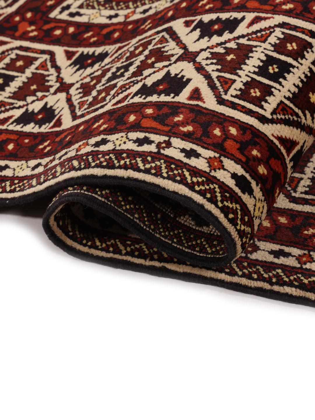 Et håndknyttet Kunduz-tæppe fra Afghanistan med geometriske motiver i rød og beige.