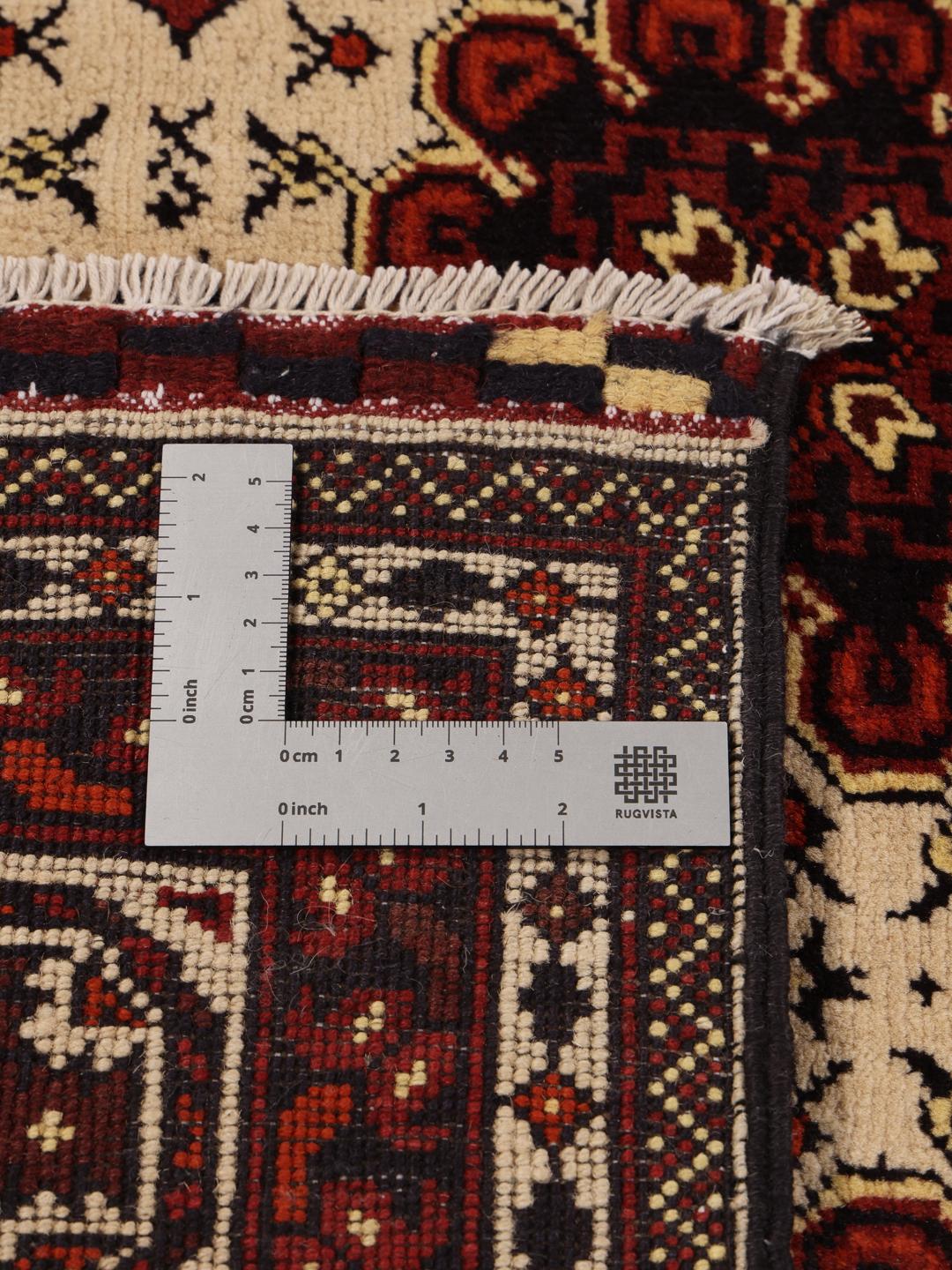 Et håndknyttet Kunduz-tæppe fra Afghanistan med geometriske motiver i rød og beige.