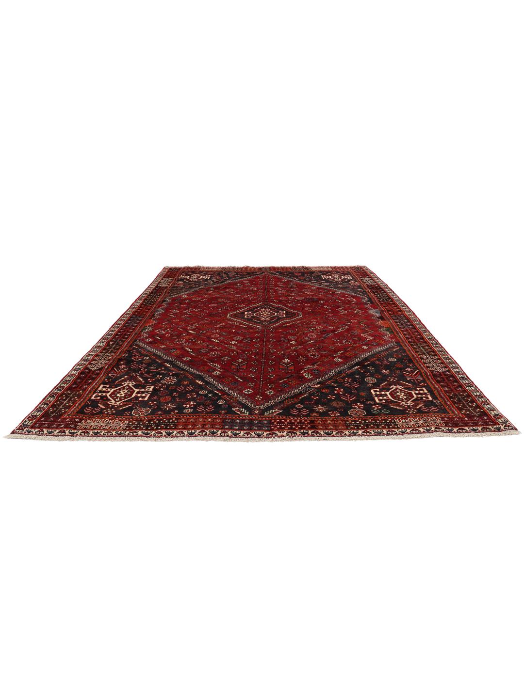 A hand-knotted Middle Eastern Ghashghai rug in red and dark tones with geometric patterns.