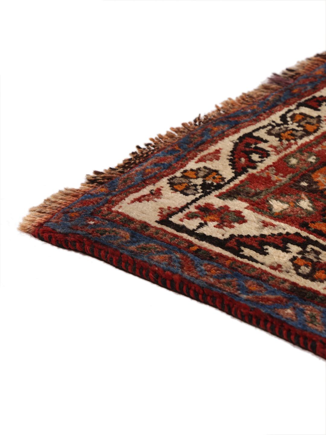 A hand-knotted Ghashghai rug from the Middle East in shades of red and black.