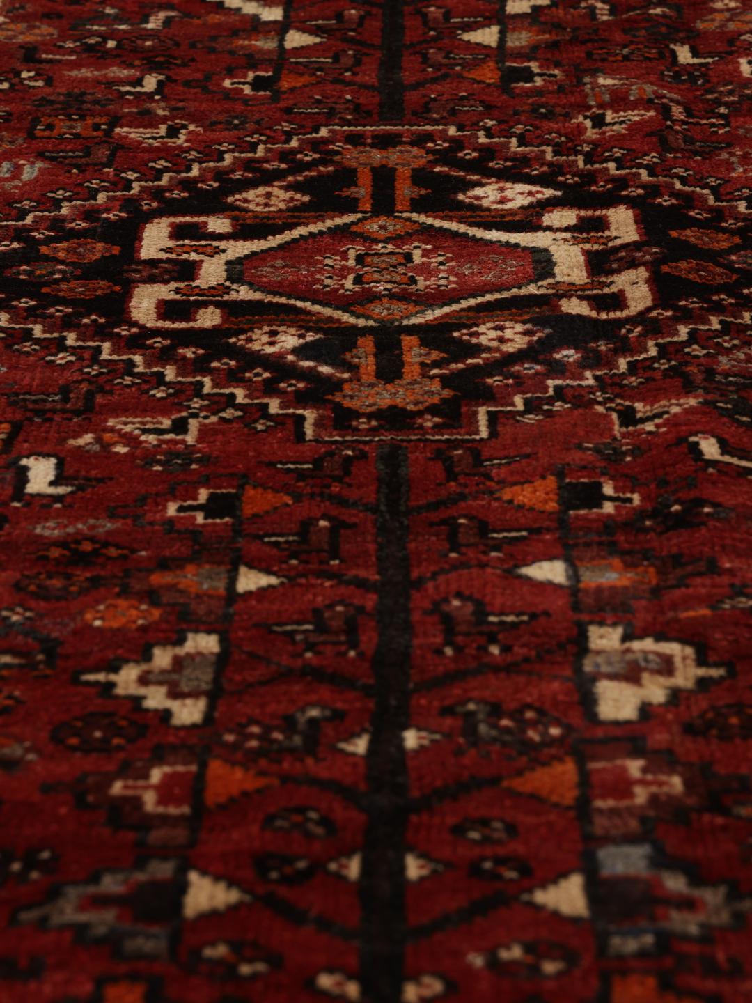 A hand-knotted Ghashghai rug from the Middle East in shades of red and black.