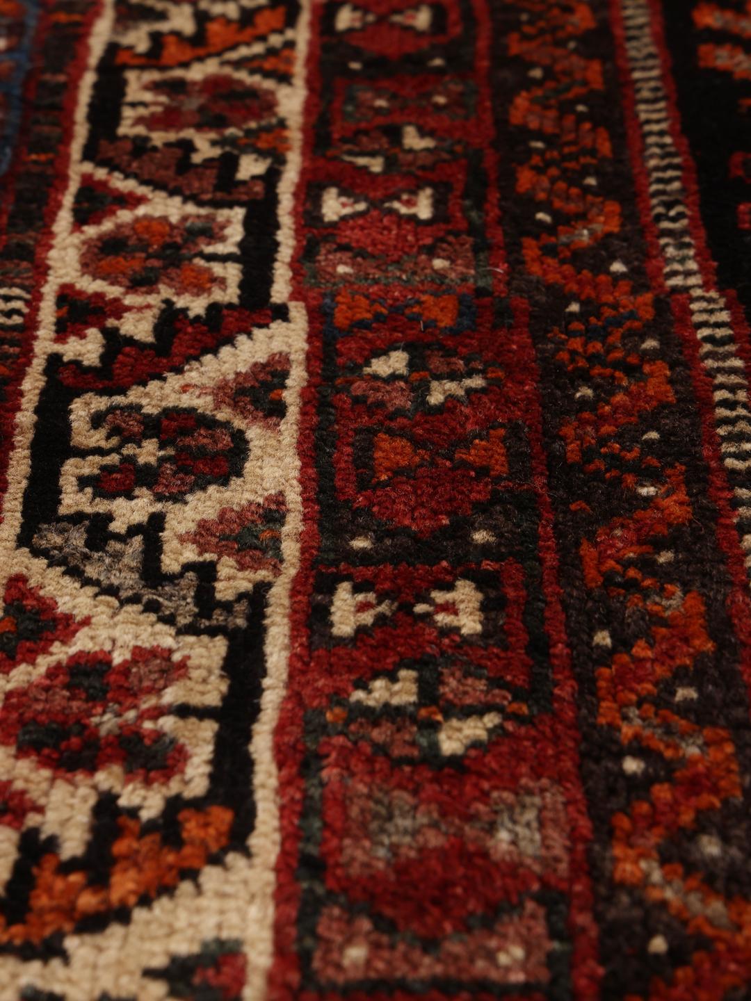 A hand-knotted Ghashghai rug from the Middle East in shades of red and black.