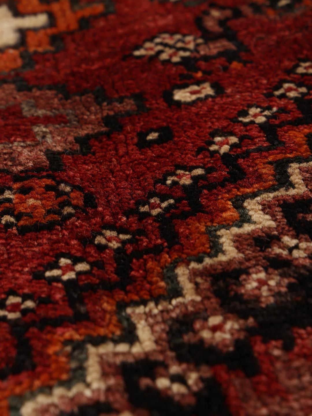 A hand-knotted Ghashghai rug from the Middle East in shades of red and black.