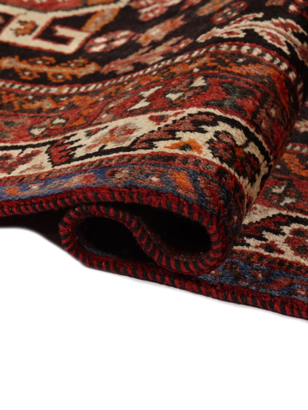 A hand-knotted Ghashghai rug from the Middle East in shades of red and black.