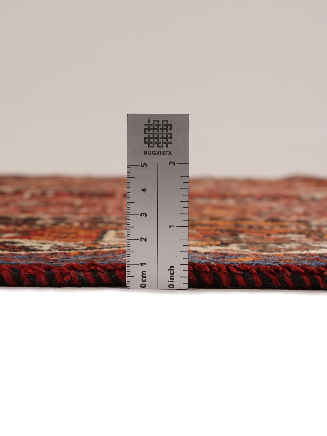 A hand-knotted Ghashghai rug from the Middle East in shades of red and black.