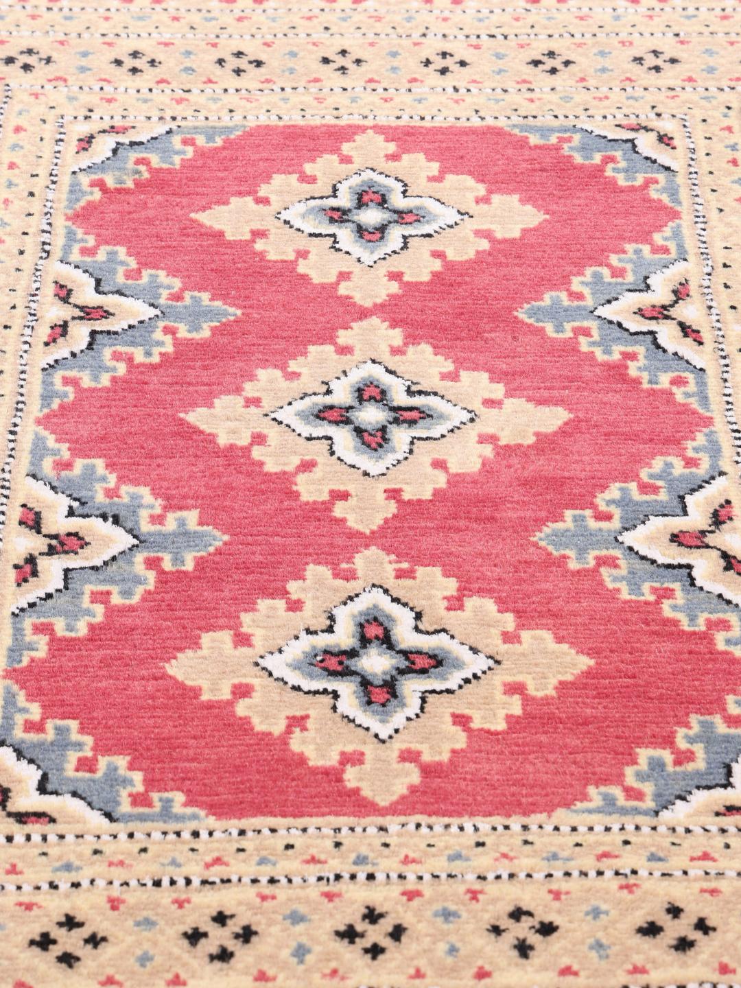 A set of two rectangular hand-knotted red Pakistan Bokhara rugs with intricate geometric patterns