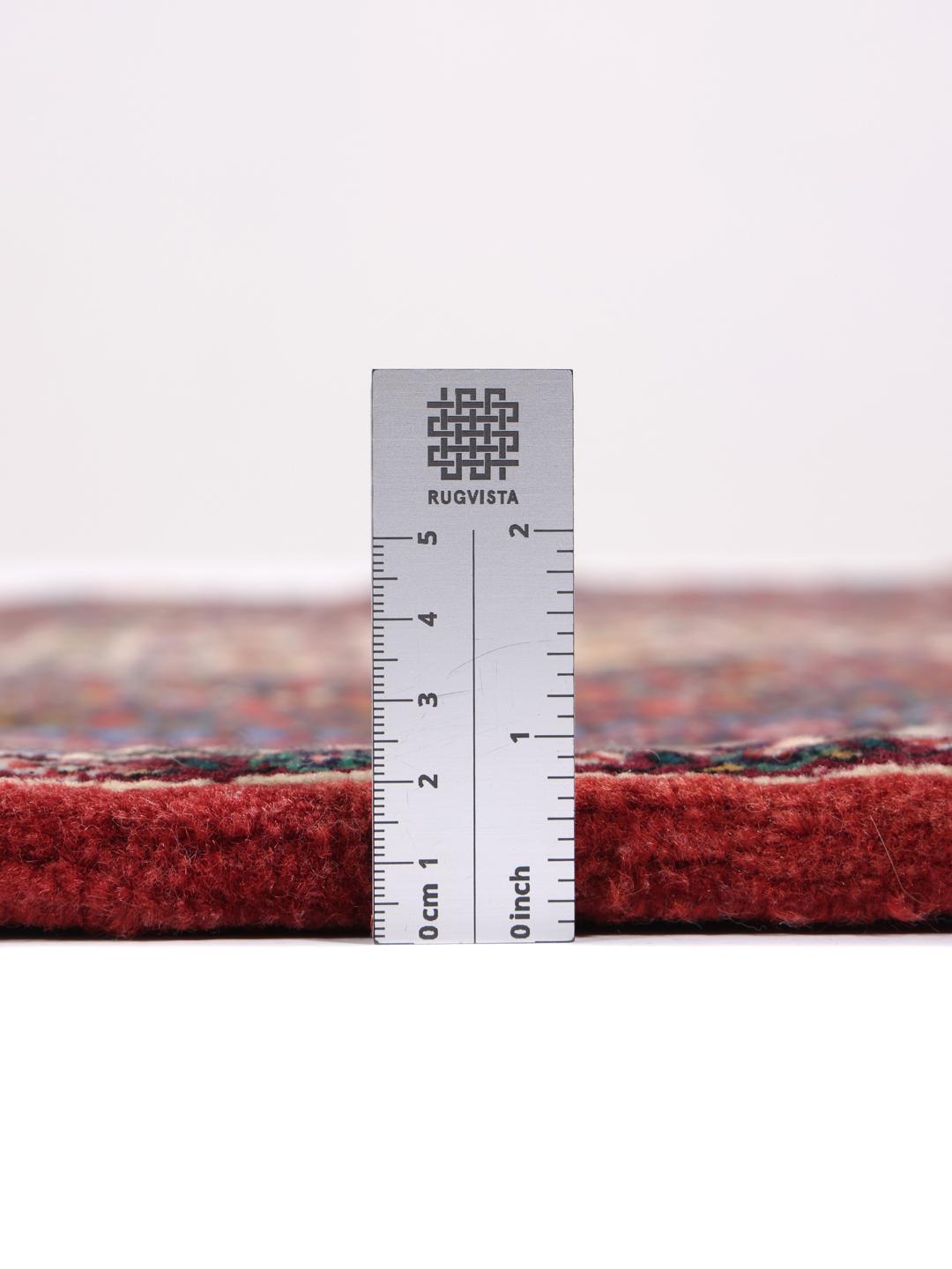 Handgeknoopt Bidjar-tapijt uit het Midden-Oosten met een rood veld en ingewikkelde patronen.
