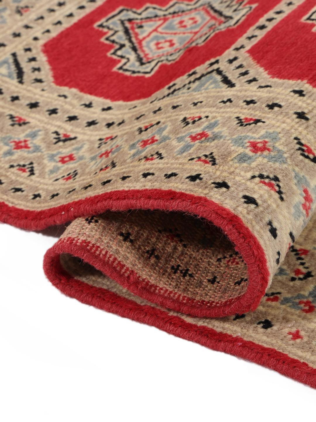 A hand-knotted Pakistan Bokhara 2ply rug with a red field and geometric motifs.