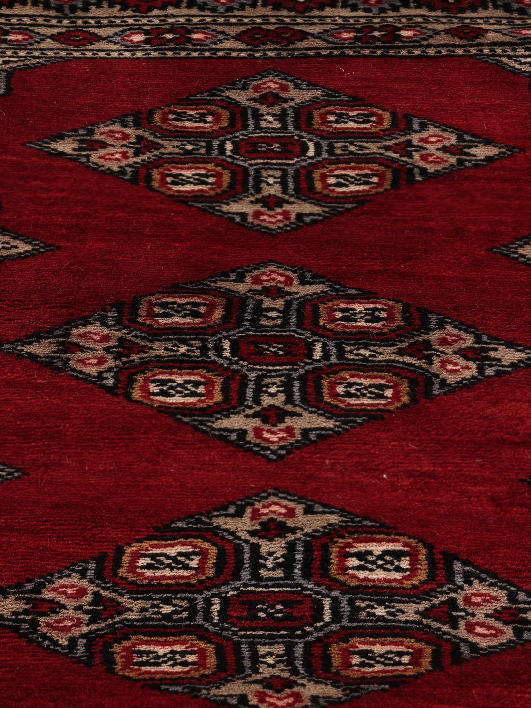 Hand-knotted Pakistan Bokhara rug with a red field and geometric motifs