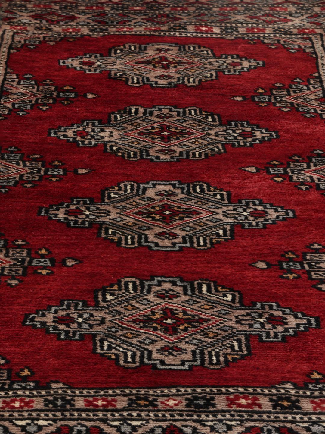 Hand-knotted Pakistan Bokhara rug with a red field and geometric motifs