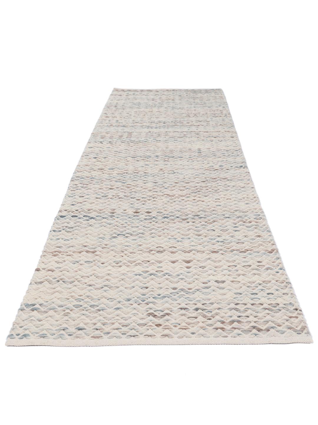 Un long tapis de couloir présentant un motif chevron délicat dans des tons de crème et de gris clair