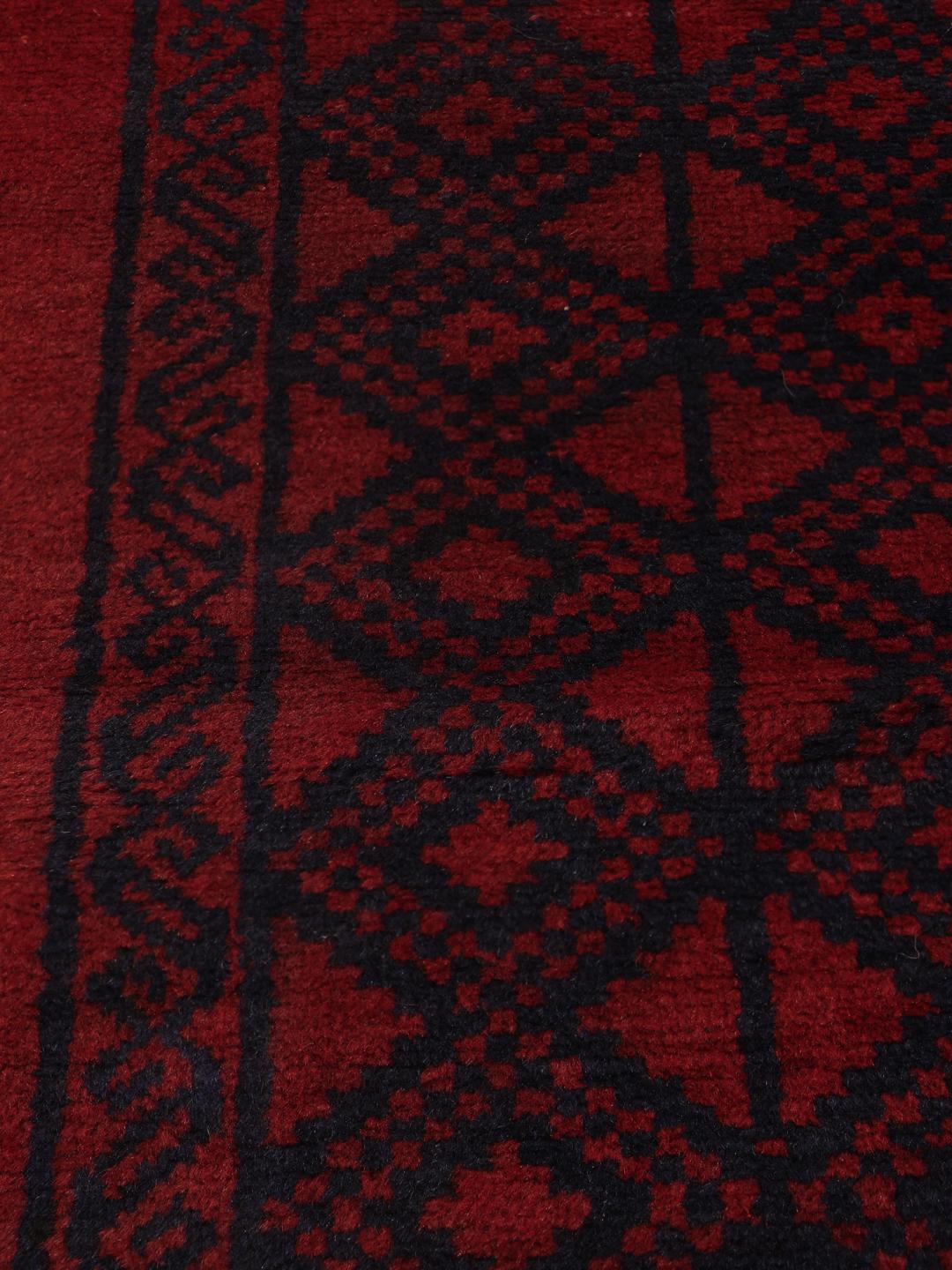 Ręcznie wiązany dywan Beluch z Afganistanu z ciemnoczerwonym i czarnym wzorem geometrycznym.