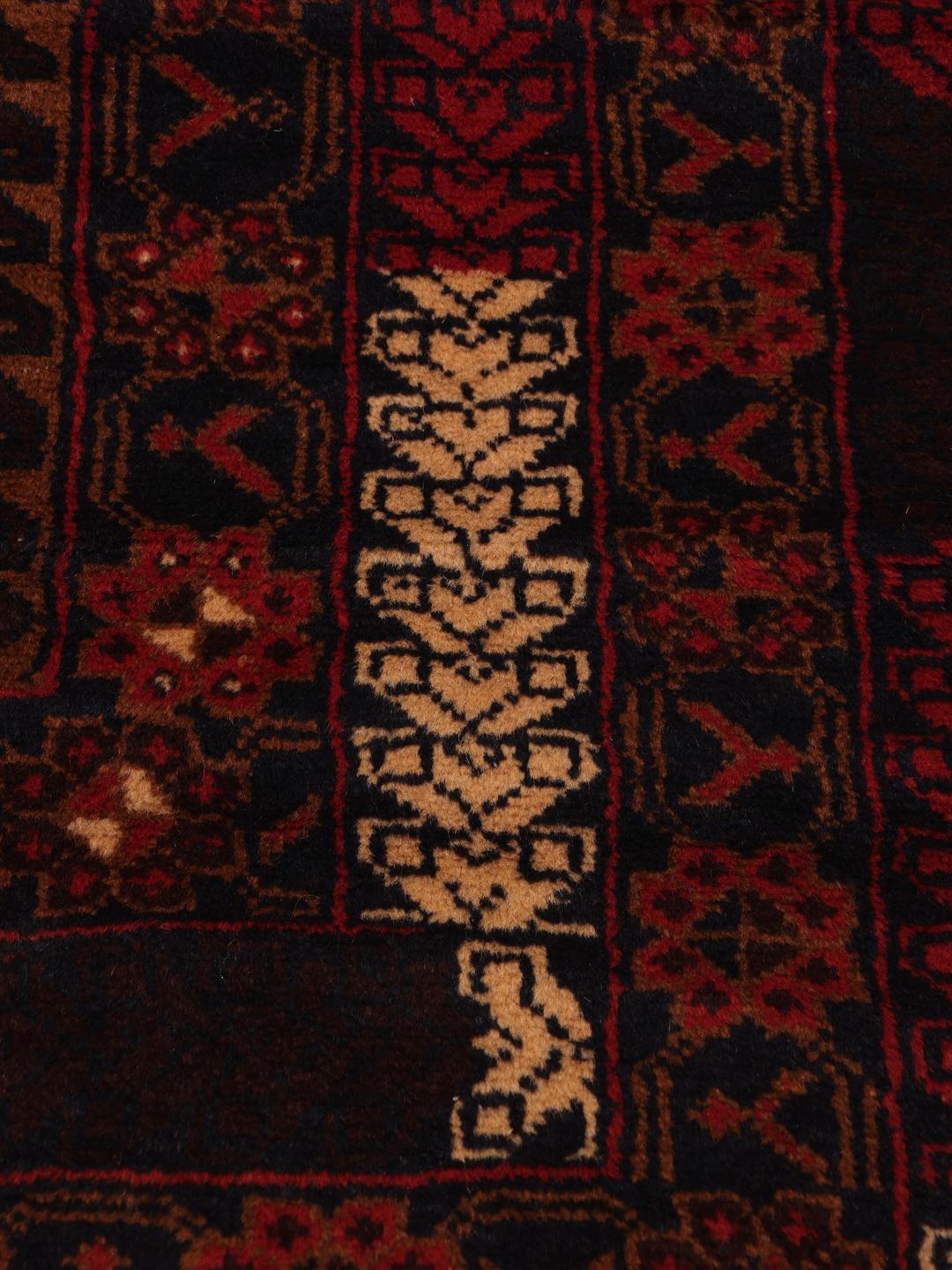Håndknyttet afghansk uldløber i dybe røde og mørke toner med geometriske mønstre.