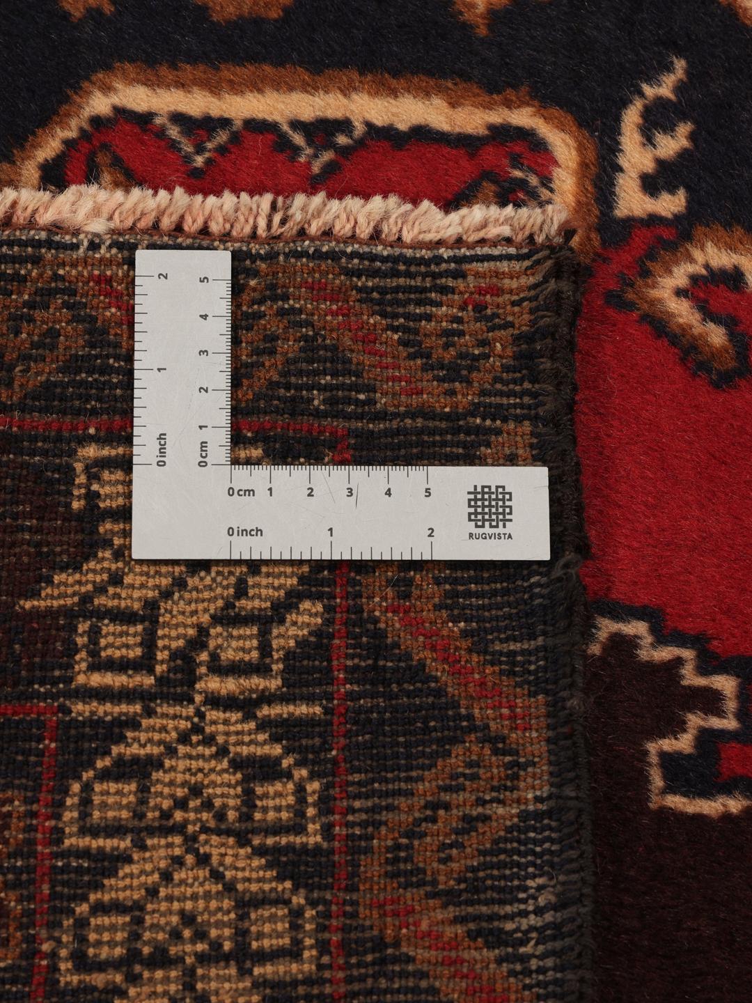 Håndknyttet afghansk uldløber i dybe røde og mørke toner med geometriske mønstre.