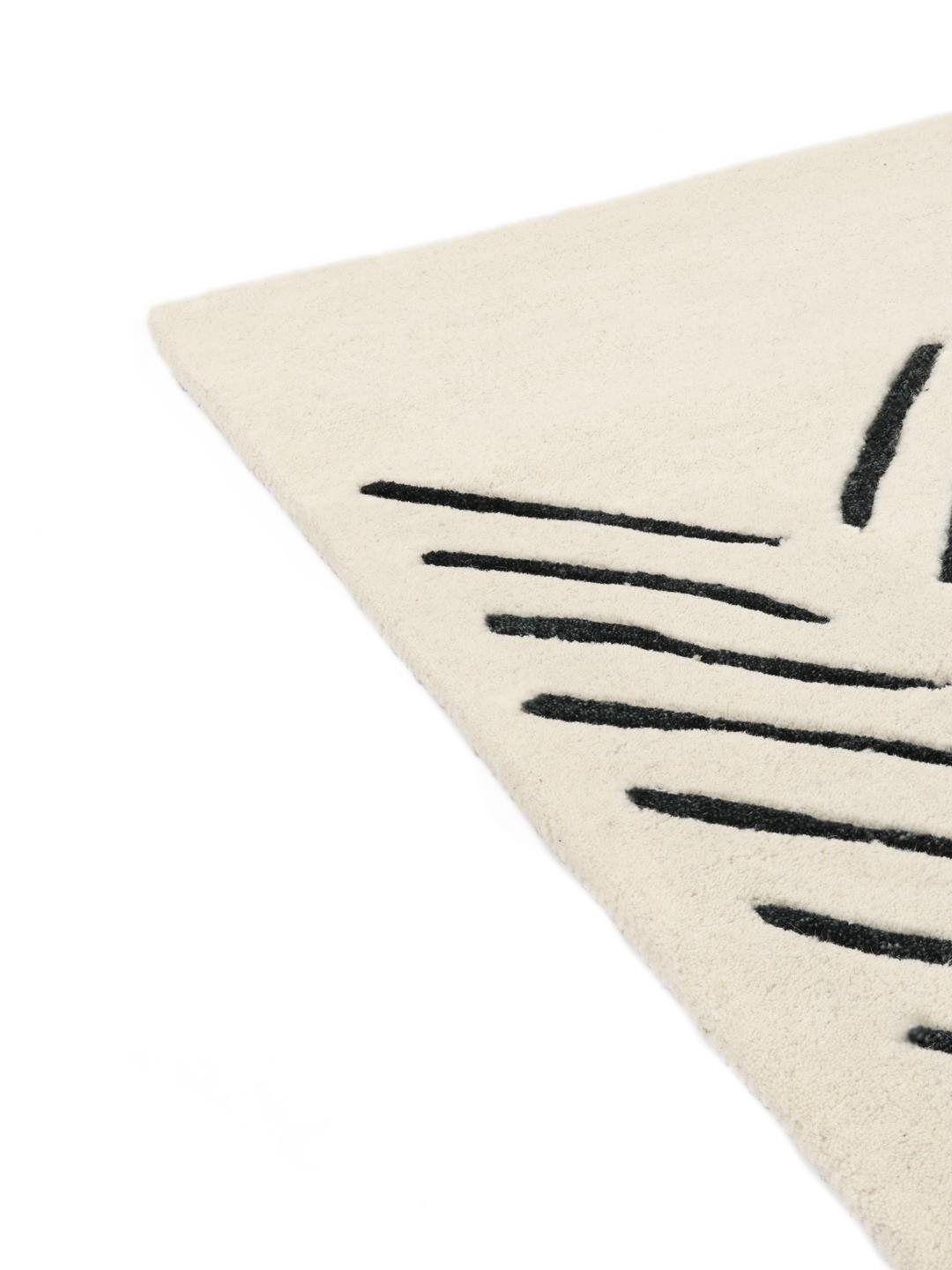 Un tappeto rettangolare con sfondo bianco e motivo chevron nero taftato a mano.