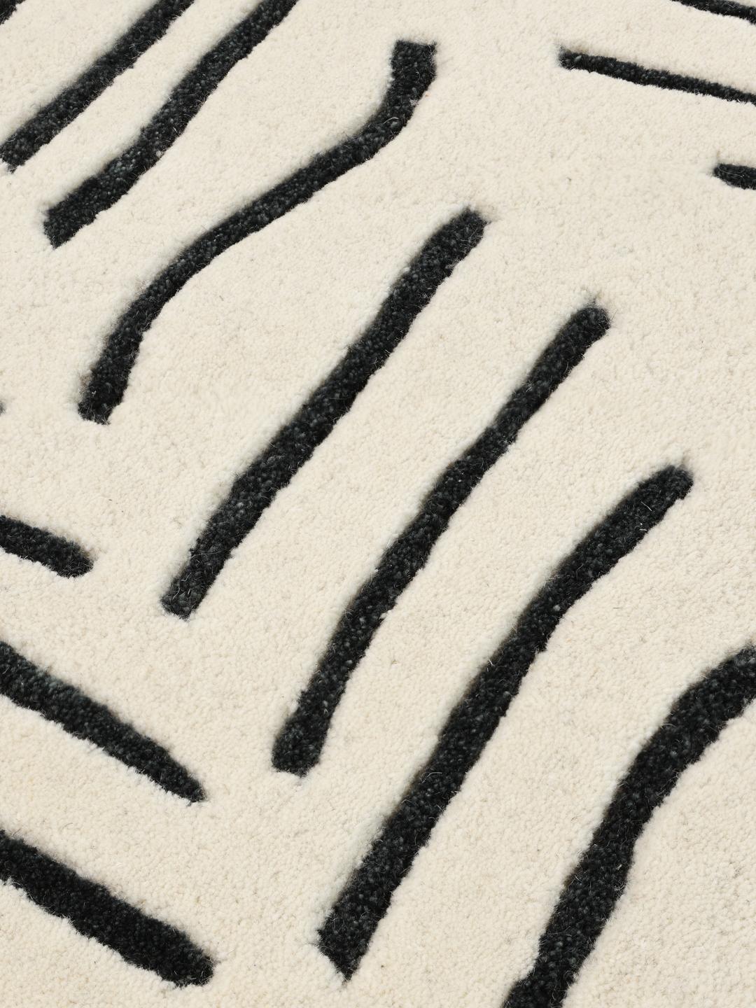 Un tappeto rettangolare con sfondo bianco e motivo chevron nero taftato a mano.