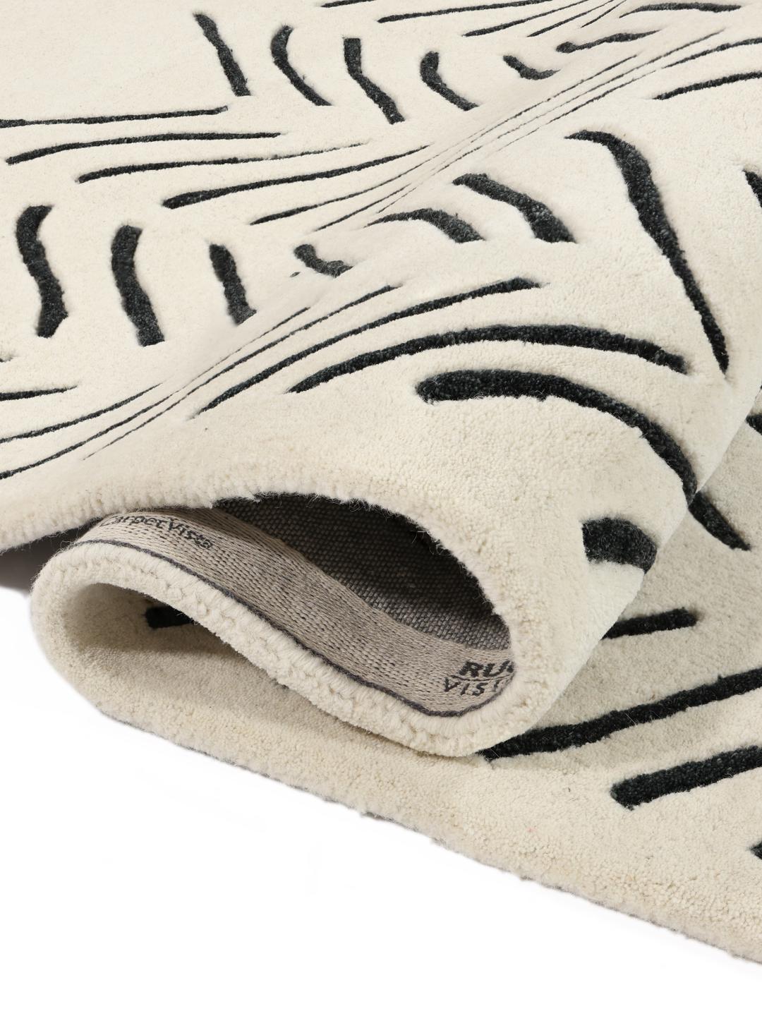 A rectangular rug with a white background and a black hand-tufted chevron pattern.