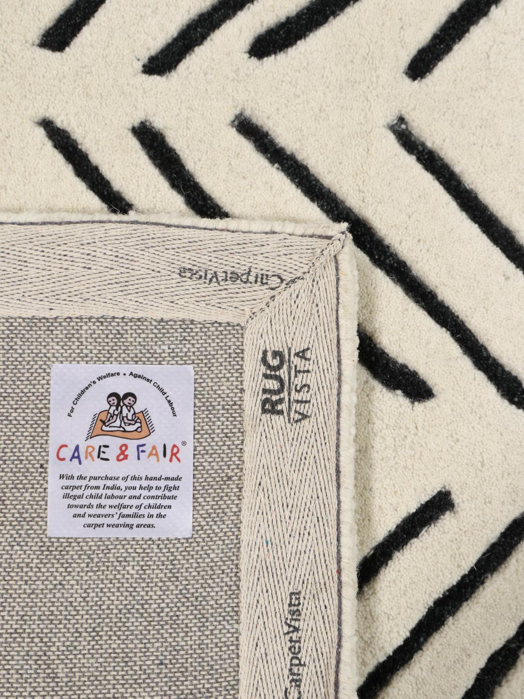 A rectangular rug with a white background and a black hand-tufted chevron pattern.