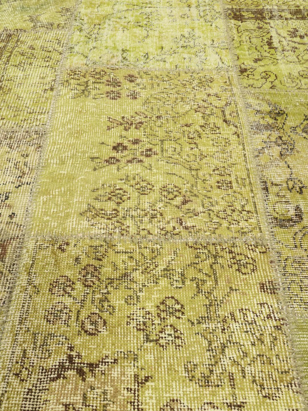 Et rektangulært håndlavet patchwork-tæppe fra Tyrkiet med en levende grøn farvepalette.