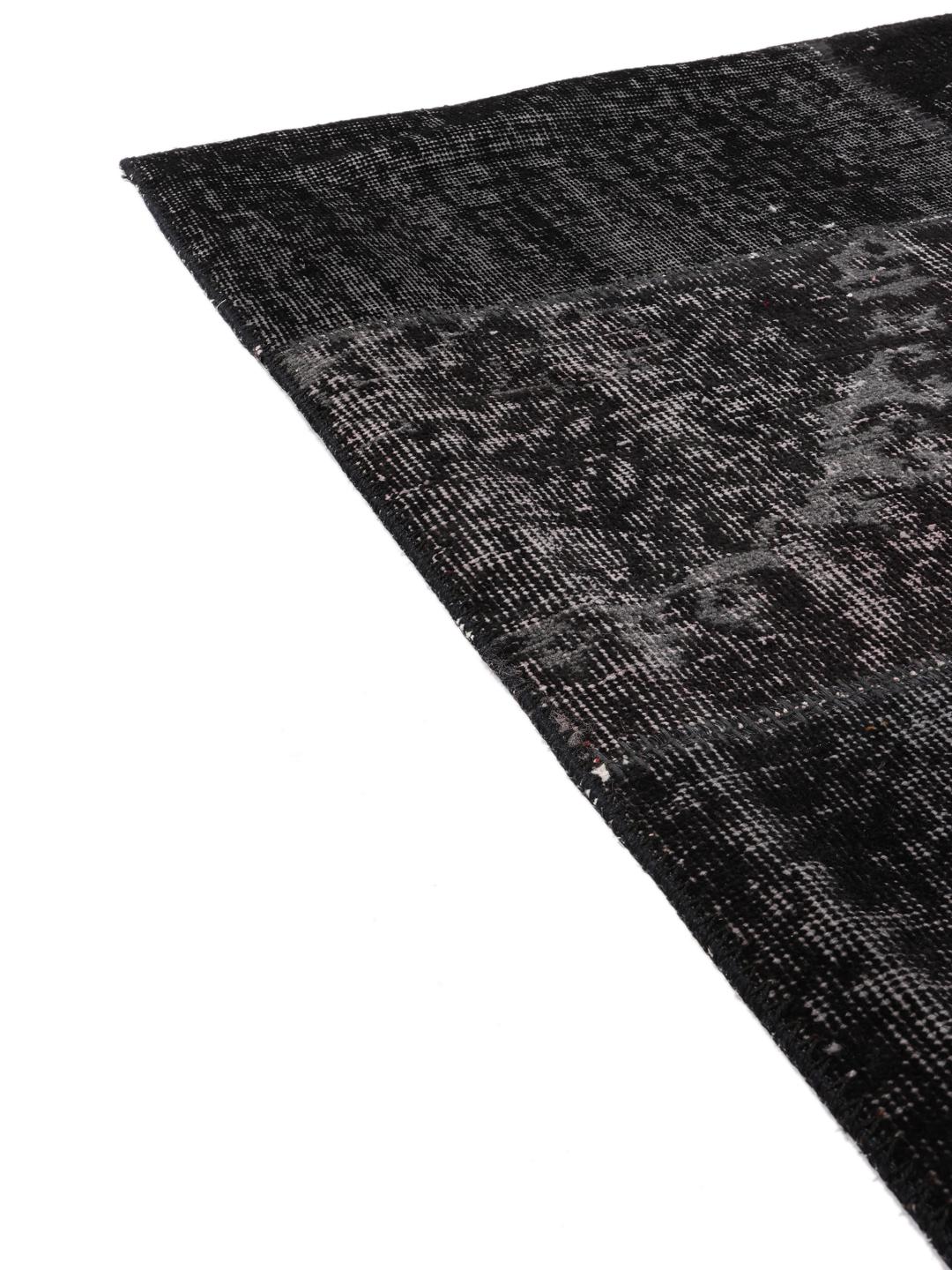 Prostokątny, czarny turecki dywan typu patchwork o tonalnym, teksturowanym wykończeniu.