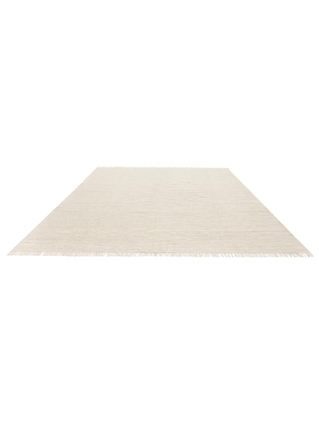 Beige tapijt met een handgeweven textuur en afgewerkt met franjes aan de uiteinden
