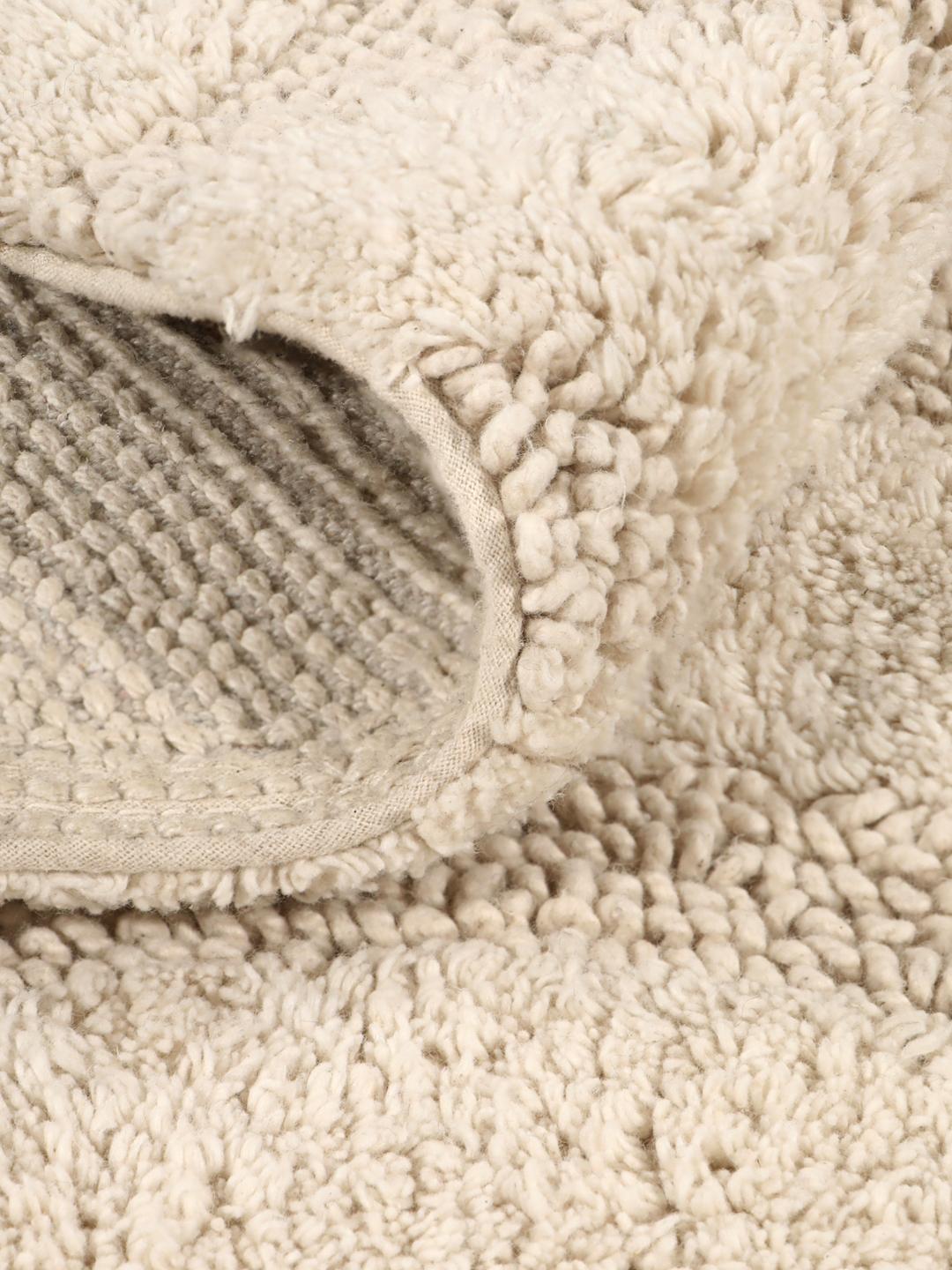 Tapis de bain beige avec un motif à rayures ondulées texturées