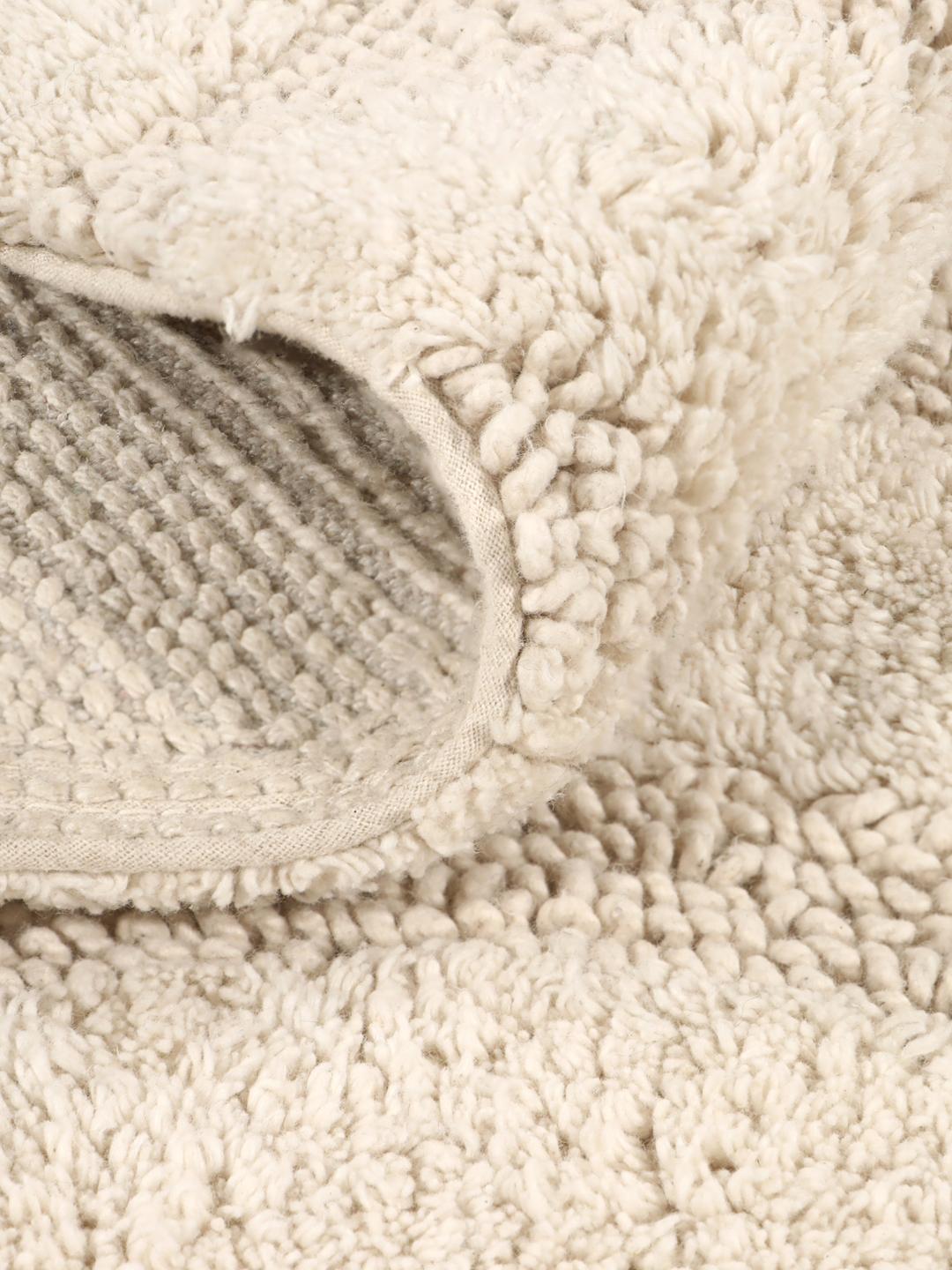 Tapis de bain rond beige avec un motif en relief ondulé texturé
