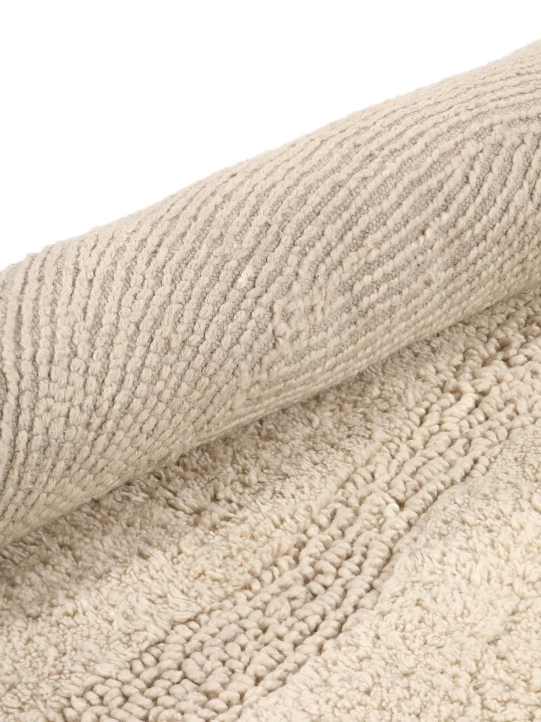 Tapis de bain rond beige avec un motif en relief ondulé texturé