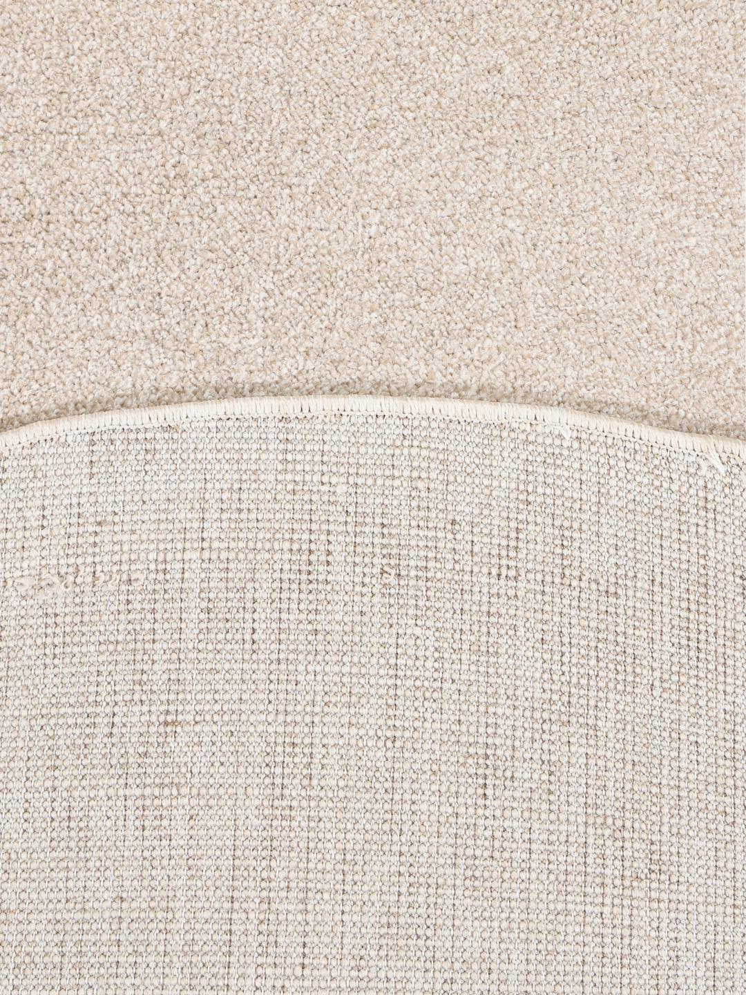 Een rond beige en geel tapijt met abstracte geometrische lijnen.