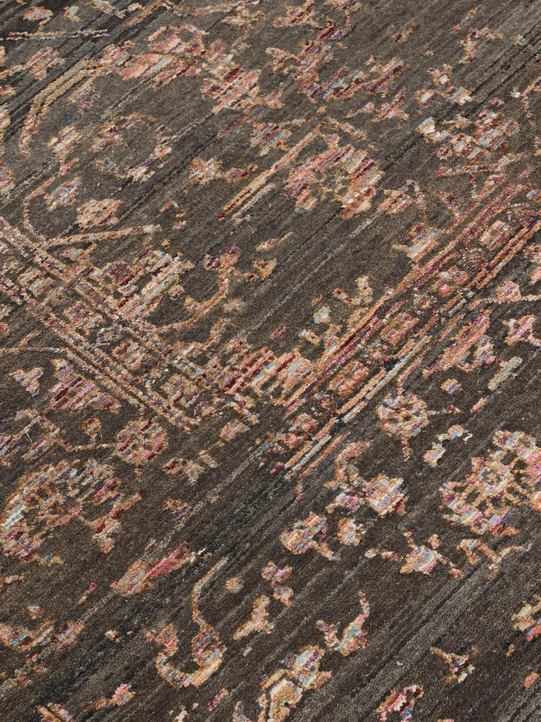 Et mørkt, sofistikeret håndknyttet tæppe fra Indien med fine blomstermotiver og en dyb, stemningsfuld farvepalette.