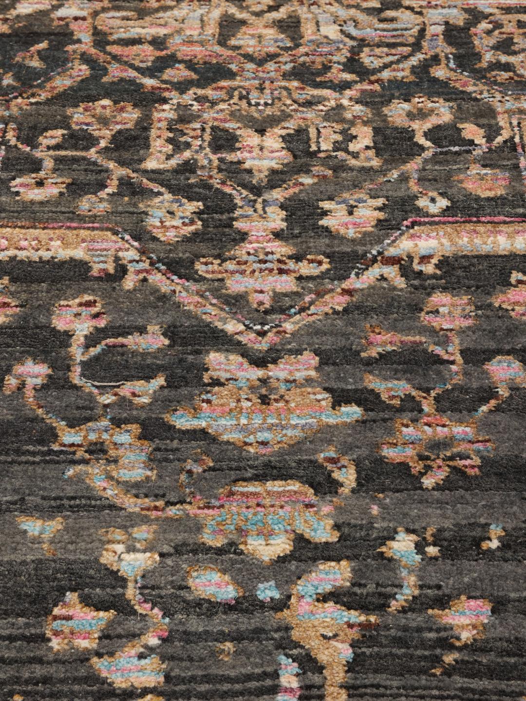Et mørkt, sofistikeret håndknyttet tæppe fra Indien med fine blomstermotiver og en dyb, stemningsfuld farvepalette.