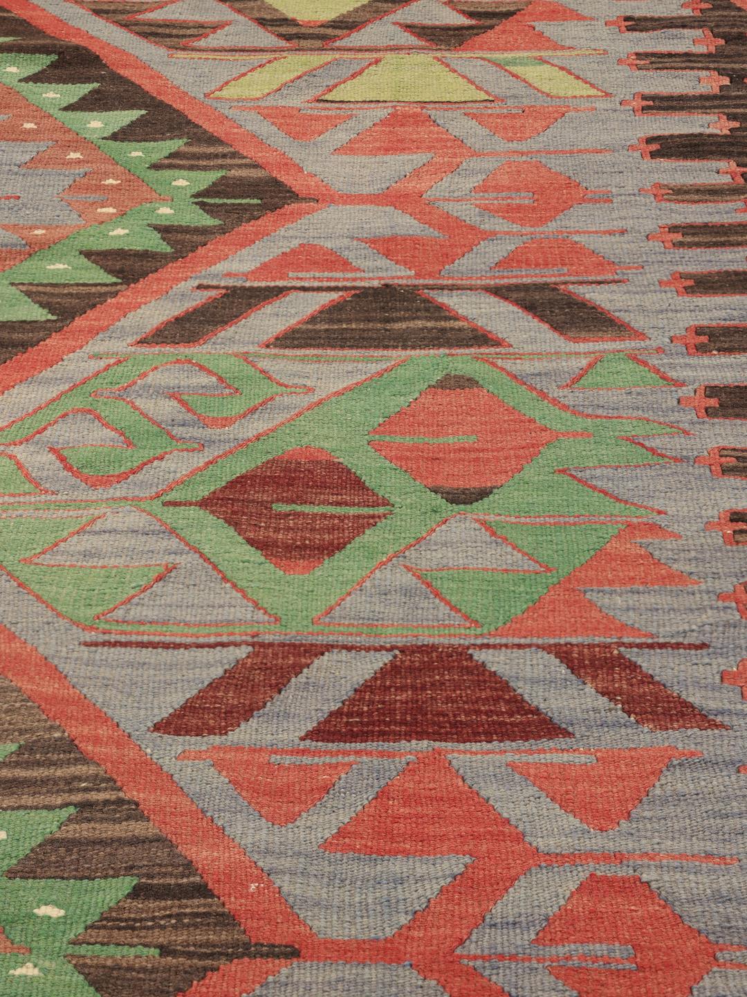 Un tapis Kelim turc vintage présentant un motif géométrique en laine multicolore.