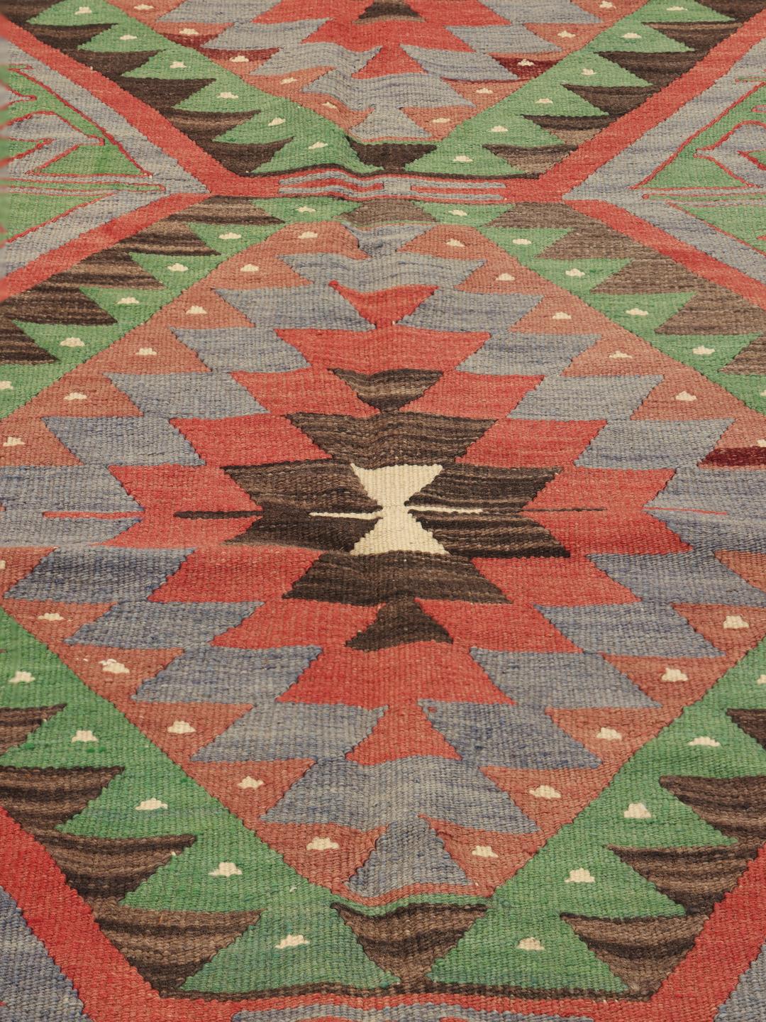 Un tapis Kelim turc vintage présentant un motif géométrique en laine multicolore.