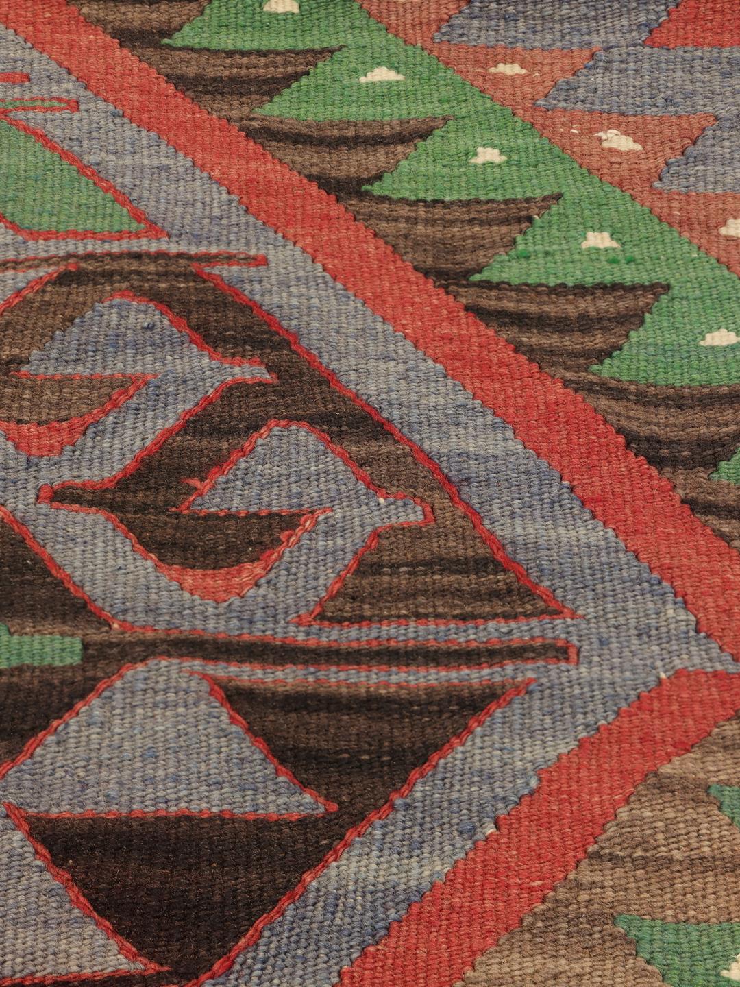 Un tapis Kelim turc vintage présentant un motif géométrique en laine multicolore.