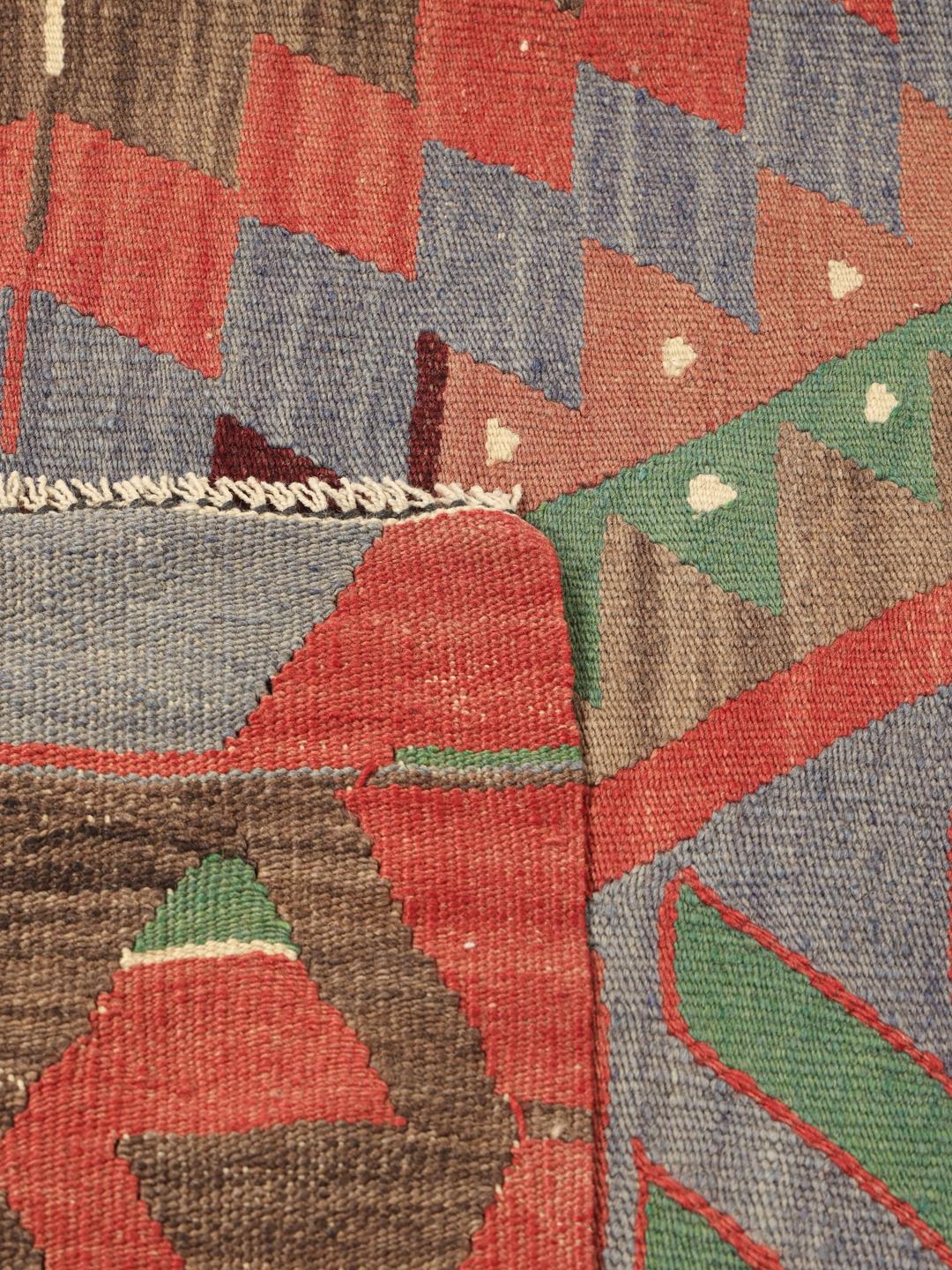 Un tapis Kelim turc vintage présentant un motif géométrique en laine multicolore.